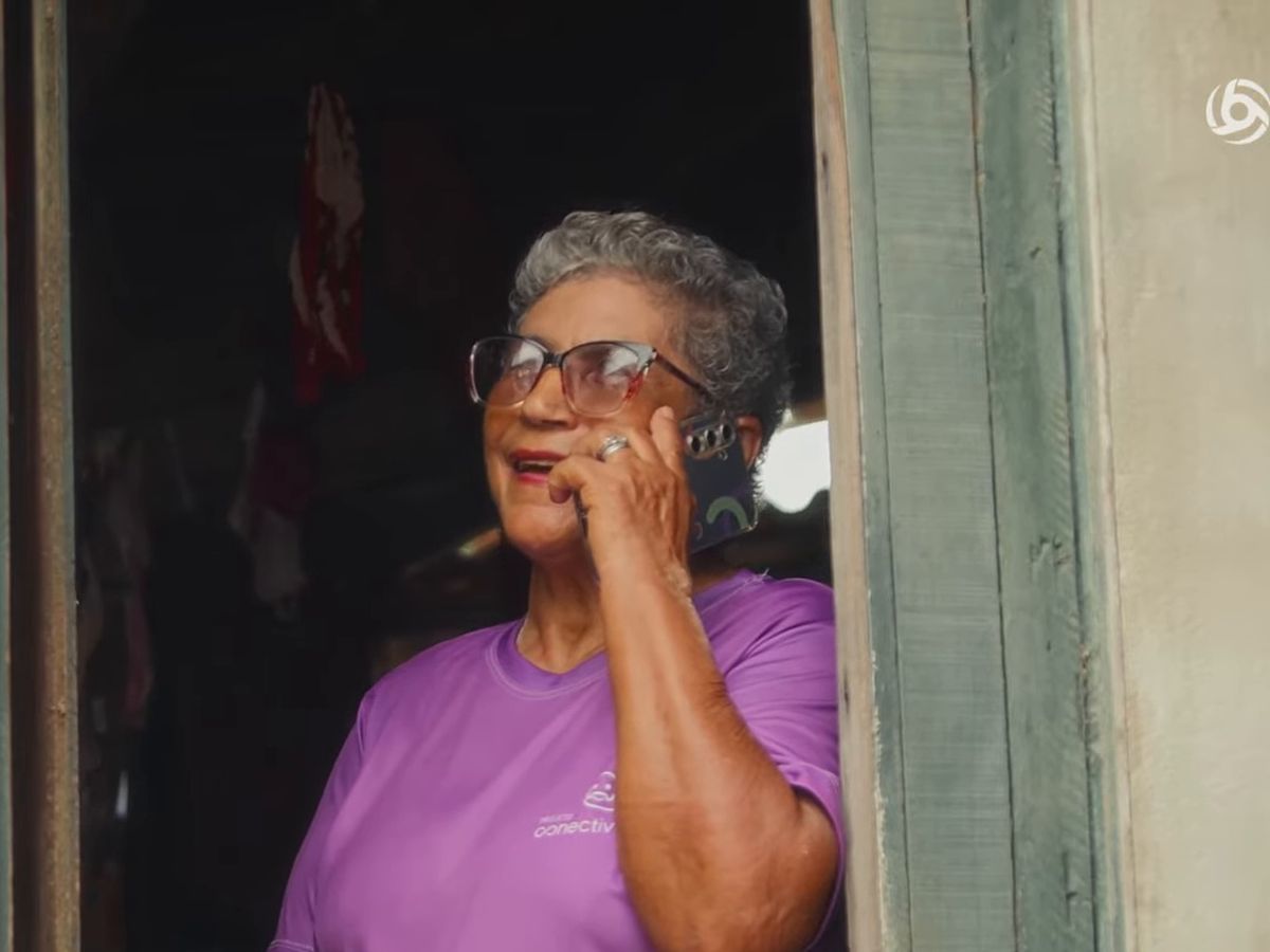 Pessoa idosa na porta de casa, falando ao celular