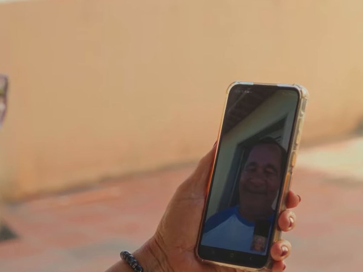 Mão segurando o celular numa chamada de vídeo