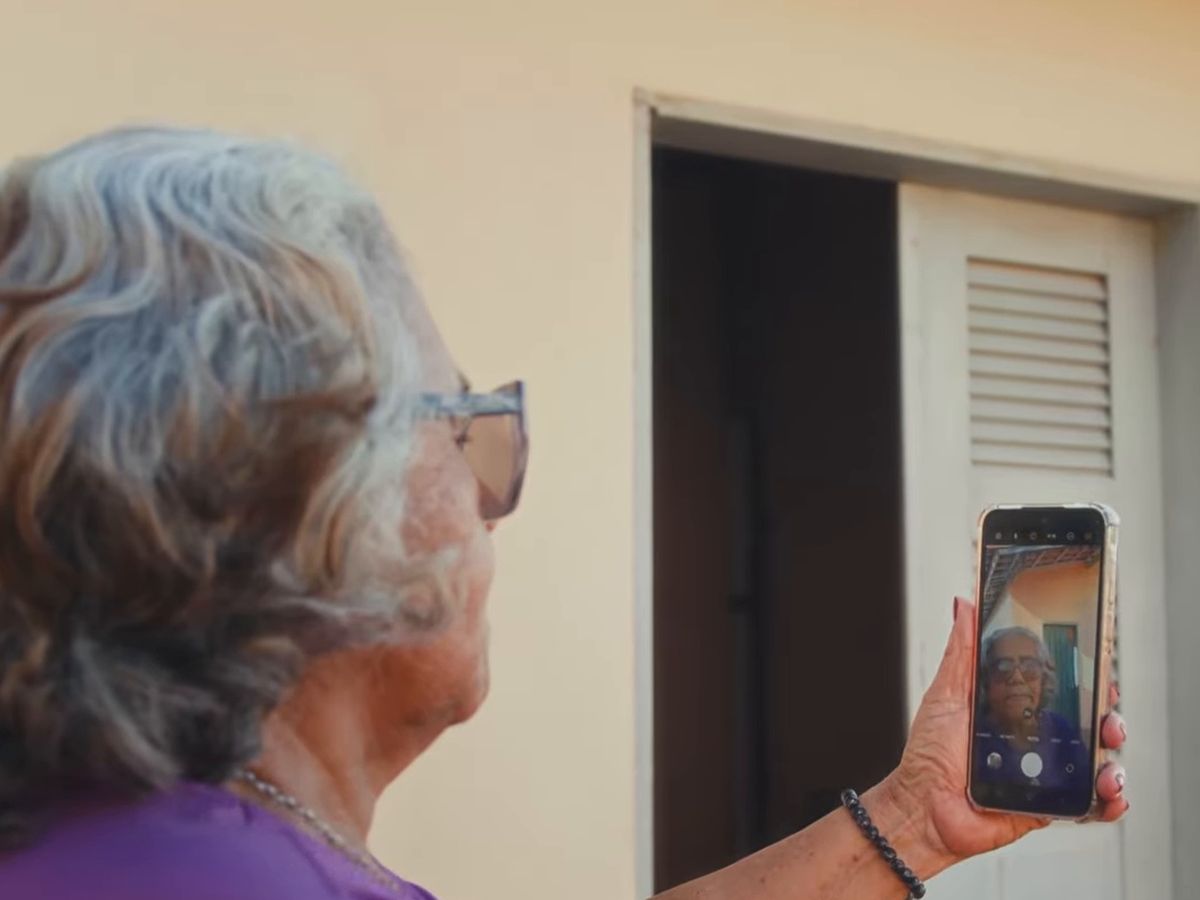 Pessoa idosa, de costas, faz uma selfie com o celular
