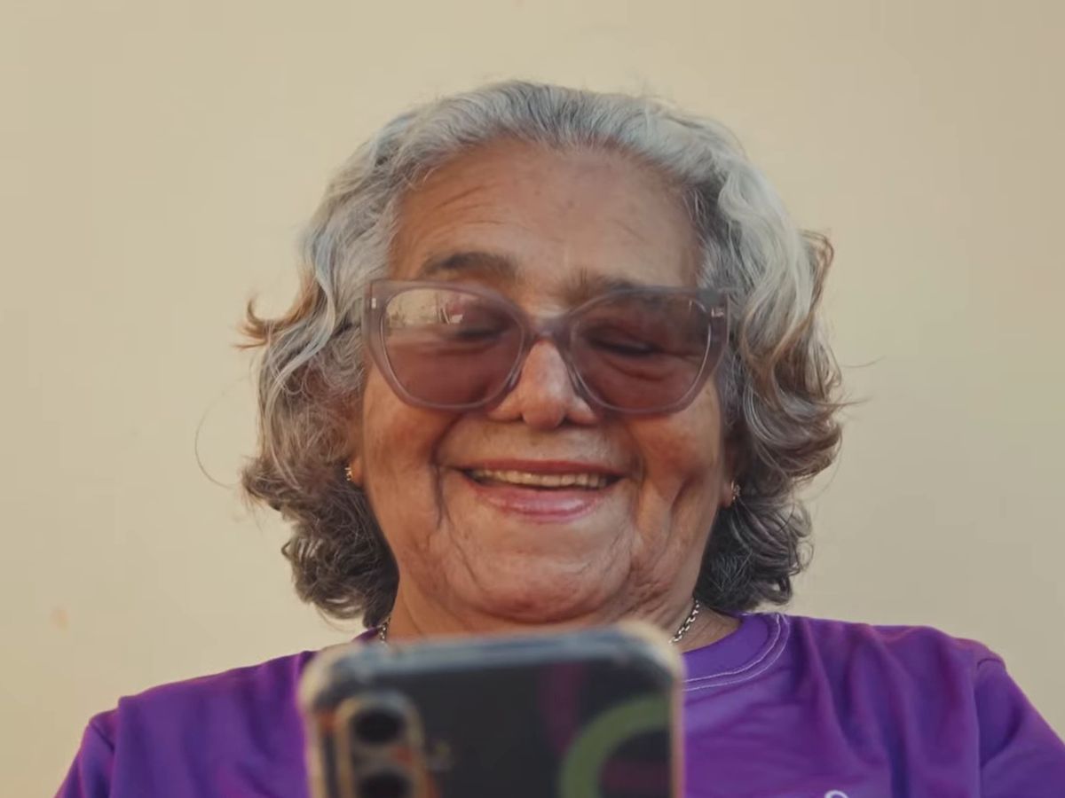 Pessoa idosa sorrindo enquanto olha o celular